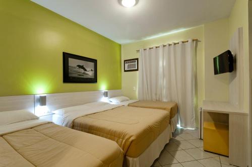 a hotel room with three beds and a tv at Pousada Villa Atlântica in Balneário Camboriú