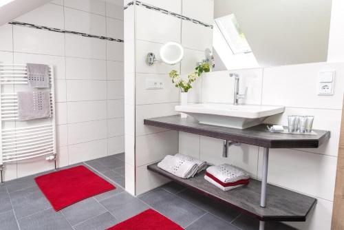 ein Badezimmer mit einem Waschbecken und einem roten Teppich in der Unterkunft Chalet Hageberg ab Mai freie Fahrt mit Bergbahnen in Bolsterlang