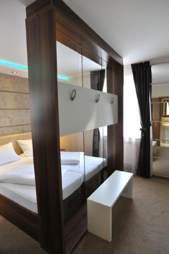 a room with two beds and a bench in it at Hotel Bergischer Hof in Ratingen