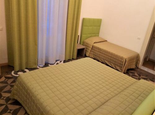 a room with two beds and a chair and curtains at Hotel Etnea Royal Suites in Catania