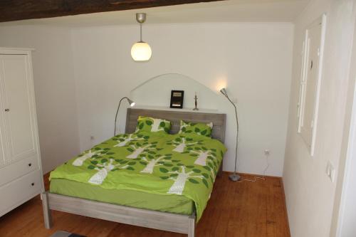 ein Schlafzimmer mit einem Bett mit einer grünen Bettdecke in der Unterkunft Akác Ház in Feked