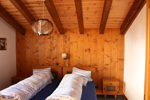two beds in a room with wooden walls at Haus-Aristella in Riederalp