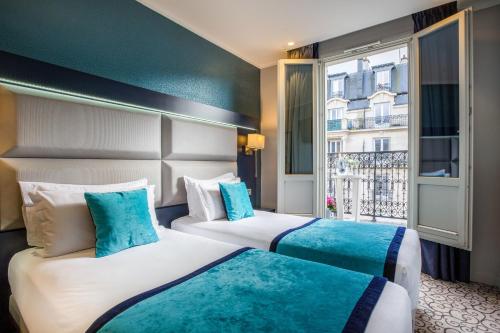 two beds in a hotel room with a window at Prince Albert Montmartre in Paris