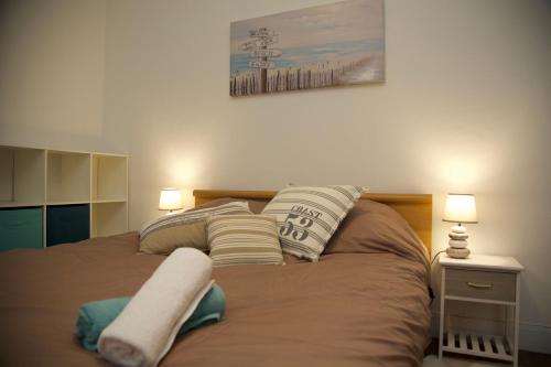 um quarto com uma cama com almofadas em Au chat qui danse, T2 tout confort Intra-Muros em Saint Malo