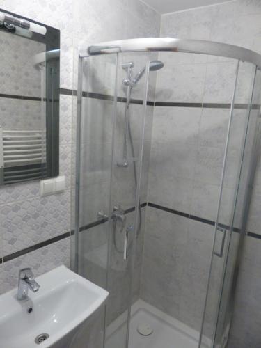 a shower with a glass door next to a sink at Pokoje u ZośkiP in Zakopane