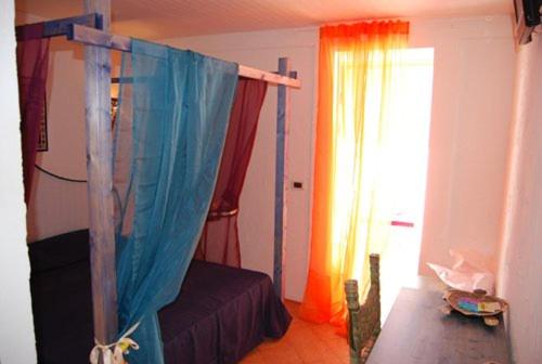 een slaapkamer met een bed en een raam met gordijnen bij Blue Bab B&B in Lampedusa