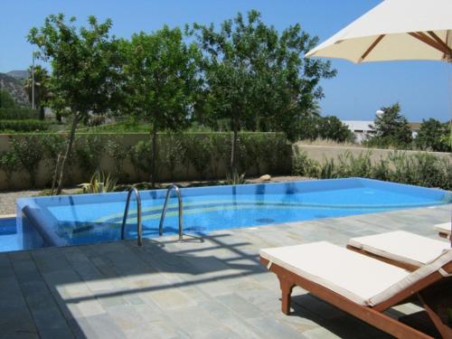 a swimming pool with an umbrella and two chairs at Amorosa Villas in Polis Chrysochous