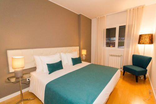 a bedroom with a large bed and a blue chair at Oriente Rio Apartments by APT IIN - Parque das Nações in Lisbon