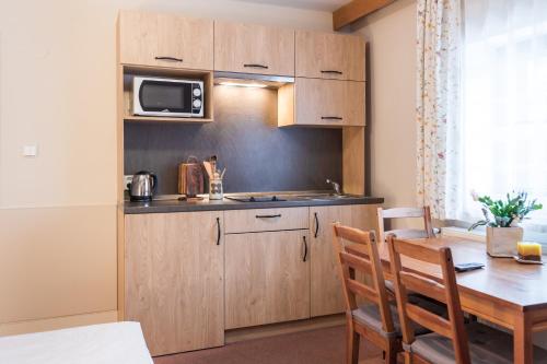 a kitchen with wooden cabinets and a wooden table with chairs at Penzion U Kaplicky in Železná Ruda