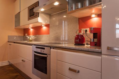 a kitchen with white cabinets and a red wall at Filip’s Palace Luxurious Apartment in Ljubljana