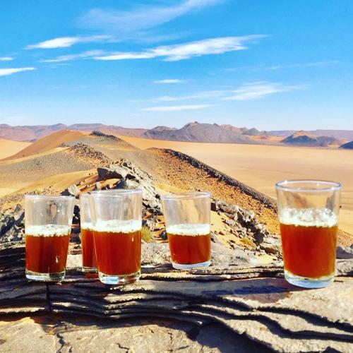 four glasses of beer sitting on a table in the desert at Riad Les Jardins de Tafraoute in Foum Mharech