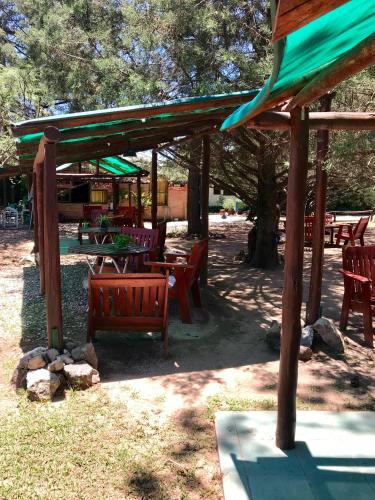 a group of picnic tables and benches under a tree at Hotel Complejo Najul Suites-Solo Adultos in Mina Clavero