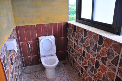 a bathroom with a toilet and a window at Phumimalee Nature View Resort in Nakhon Ratchasima