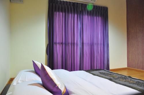 a bedroom with purple curtains and a bed with pillows at Phumimalee Nature View Resort in Nakhon Ratchasima