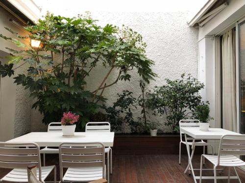 two tables and chairs on a patio with plants at Maison d'hôtes Bordeaux Centre Le Patio de l'Intendance in Bordeaux