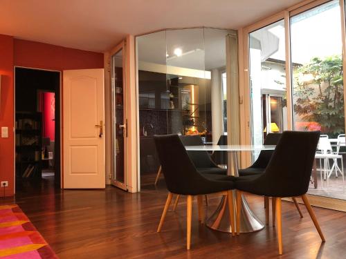 a dining room with a glass table and black chairs at Maison d'hôtes Bordeaux Centre Le Patio de l'Intendance in Bordeaux