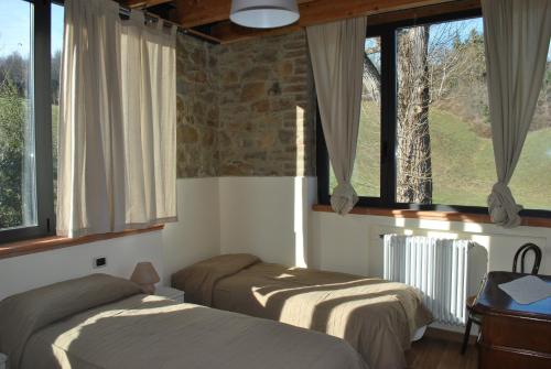 two beds in a room with large windows at Agriturismo Petrarosa in Neviano degli Arduini
