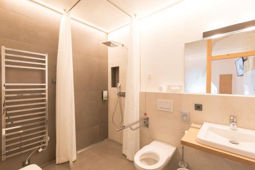 a bathroom with a shower and a toilet and a sink at Belvenu Boutique Hotel in Glorenza