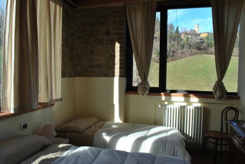 a bedroom with two beds and a large window at Agriturismo Petrarosa in Neviano degli Arduini
