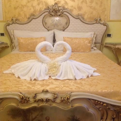 two white swansuitsrendered to look like they are kissing on a bed at La Dea Hestia in Bosa