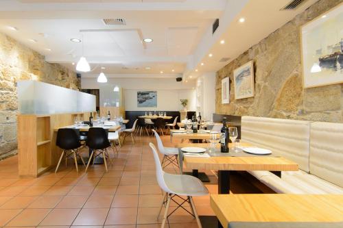 a restaurant with wooden tables and white chairs at Pazo de Mendoza in Baiona