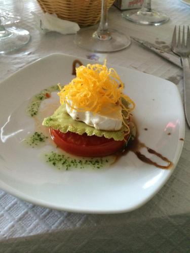 a white plate with a sandwich with cheese and a tomato at Hotel y Bungalows Balcón de Competa in Cómpeta