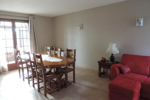 a living room with a table and a red couch at Le jardin des paons in Issac