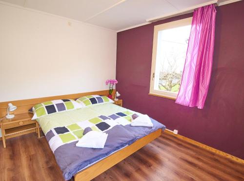 a bedroom with a bed with purple walls and a window at New West Station in Interlaken
