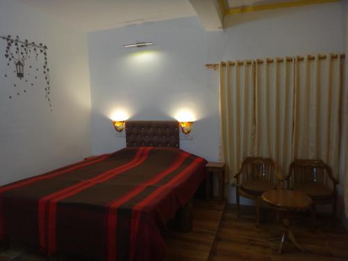 a bedroom with a bed with a red blanket and two chairs at Aqua De Vida in Bhowāli