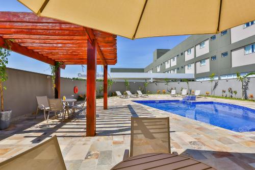 a patio with a swimming pool and a building at Comfort Mogi Guaçu in Mogi Guaçu