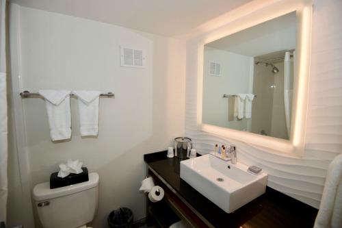 a white bathroom with a sink and a mirror at Ramada by Wyndham Austin South in Austin