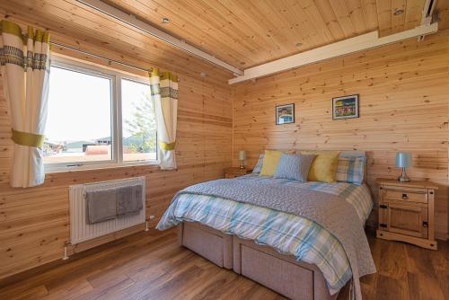 a bedroom with a bed in a wooden cabin at The Chalet, Holidays for All in Dunbar