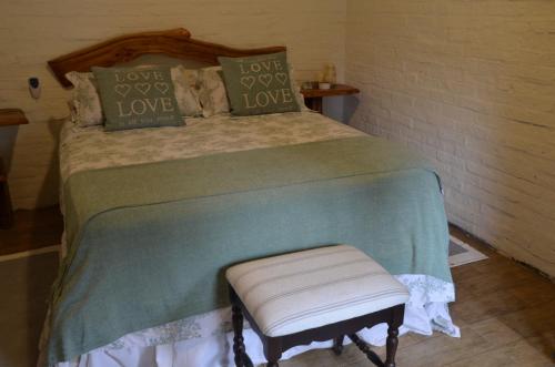 1 dormitorio con cama con almohadas de amor y taburete en Los Superabuelos, en La Pedrera