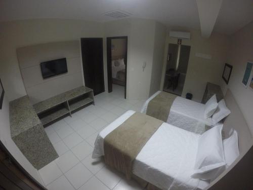 a large hotel room with two beds and a television at Pousada Doluar in Penha