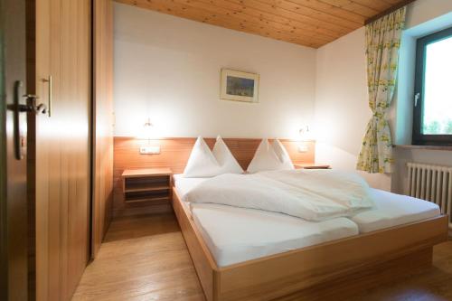 a bedroom with a bed with white sheets and pillows at Ferienhaus Schiwiese mit freiem Eintritt in die Alpentherme in Bad Hofgastein