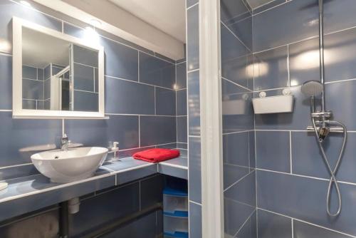 La salle de bains bleue est pourvue d'un lavabo et d'un miroir. dans l'établissement Appartement le St Roch, à Montpellier