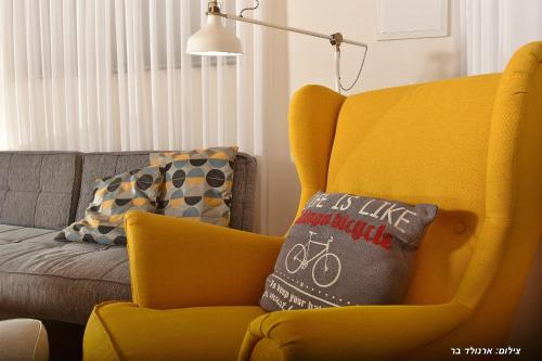 a yellow chair with a pillow in a living room at Halom Be'Dor in Dor