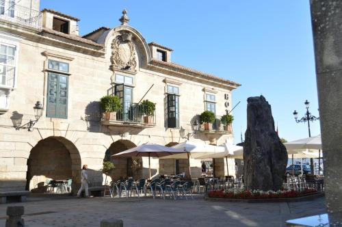 um edifício com mesas e cadeiras em frente em Pazo de Mendoza em Baiona