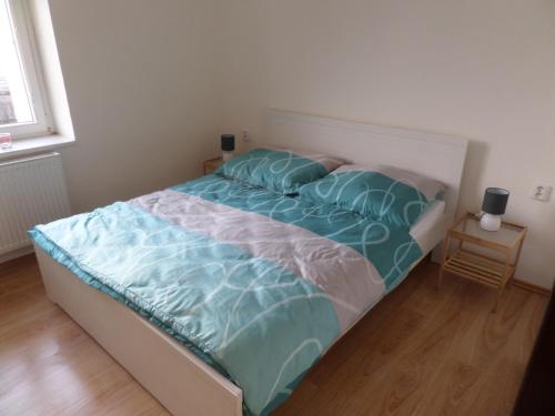 a bed with blue sheets and pillows in a bedroom at Apartmány Trutnov Promenáda in Trutnov
