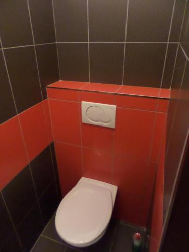 a bathroom with a white toilet in a red tile wall at Apartmány Trutnov Promenáda in Trutnov