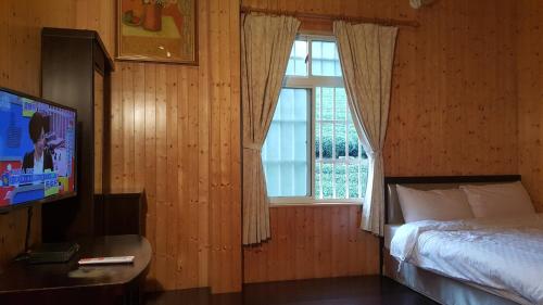 Schlafzimmer mit einem Bett, einem TV und einem Fenster in der Unterkunft Ming Yang B&B in Fenchihu