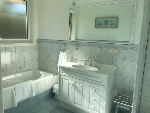 Taras Richmond Farmstay في ريتشموند: حمام أبيض مع حوض ومغسلة وحوض استحمام