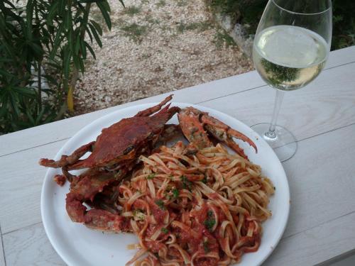 a plate of pasta with lobster and a glass of wine at Villa Soleanna Residence in Vieste