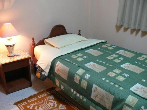 1 dormitorio con 1 cama y 1 mesa con lámpara en Hostal Vista Hermosa, en Chachapoyas