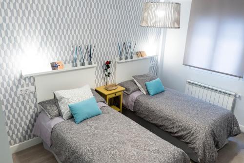 a bedroom with two beds with blue pillows at Apartamento Garval Valladolid in Valladolid