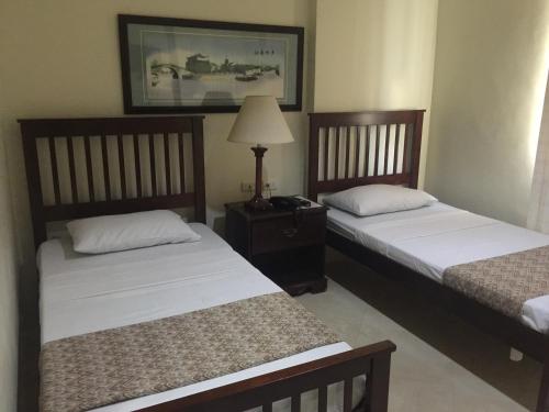 a bedroom with two beds and a table with a lamp at Metro Vigan Inn in Vigan
