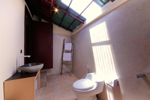 a bathroom with a toilet and a sink and a window at Sari Gili Bungalow in Gili Air