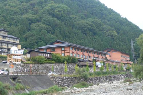a building on the side of a mountain next to a river at Yuttarino-Sato Inaka in Achi