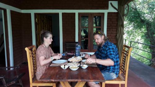a man and woman sitting at a wooden table at Elephant Trio Sigiriya in Sigiriya