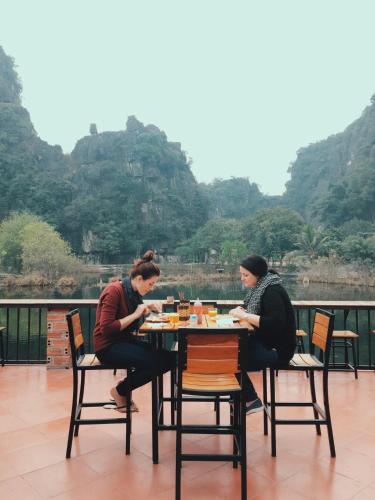 dos mujeres sentadas en una mesa frente a una montaña en Tam Coc Bungalow, en Ninh Binh